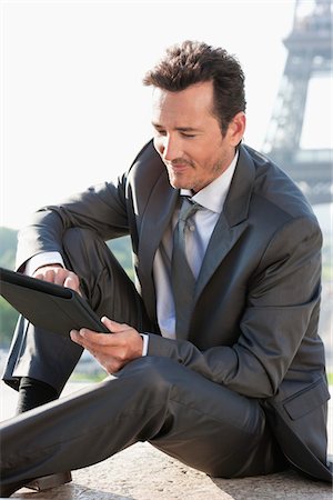 Businessman using a digital tablet with the Eiffel Tower in the background, Paris, Ile-de-France, France Stock Photo - Premium Royalty-Free, Code: 6108-05872891