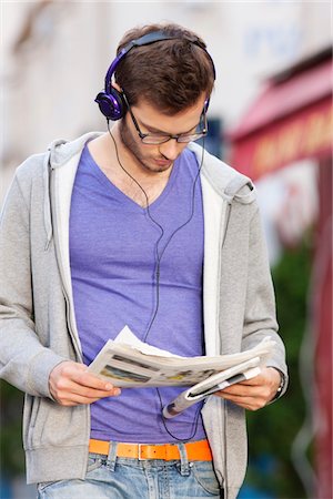 Man reading a newspaper while listening to music, Paris, Ile-de-France, France Stock Photo - Premium Royalty-Free, Code: 6108-05873032