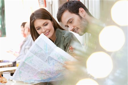 Couple sitting at a sidewalk cafe and reading a map, Paris, Ile-de-France, France Stock Photo - Premium Royalty-Free, Code: 6108-05873242