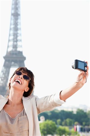 Woman taking a picture of herself with the Eiffel Tower in the background, Paris, Ile-de-France, France Stock Photo - Premium Royalty-Free, Code: 6108-05873302