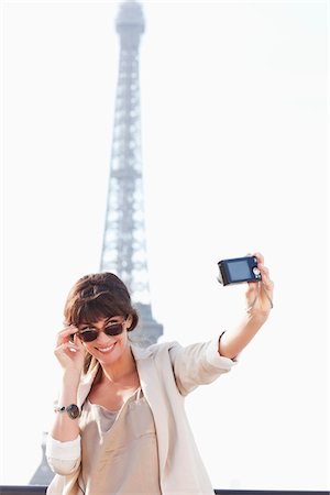 Woman taking a picture of herself with the Eiffel Tower in the background, Paris, Ile-de-France, France Stock Photo - Premium Royalty-Free, Code: 6108-05873325