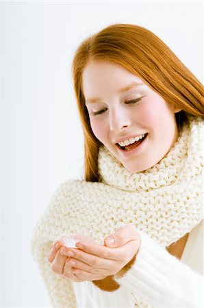 Close-up of a young woman holding snow in cupped hands and smiling Stock Photo - Premium Royalty-Free, Code: 6108-05873574