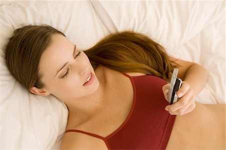 simsearch:6108-05857751,k - Portrait of a young woman lying on a bed, holding her cell Stock Photo - Premium Royalty-Free, Code: 6108-05873530