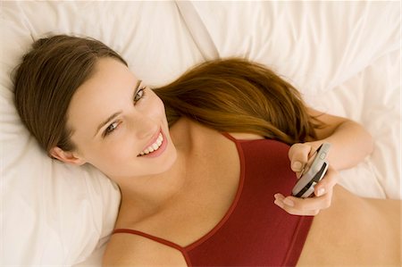 simsearch:6108-05857751,k - Portrait of a young woman lying on a bed, holding her cell Stock Photo - Premium Royalty-Free, Code: 6108-05873531