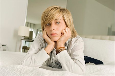 simsearch:6108-05863386,k - Teenage boy lying on the bed and looking serious Stock Photo - Premium Royalty-Free, Code: 6108-05873668