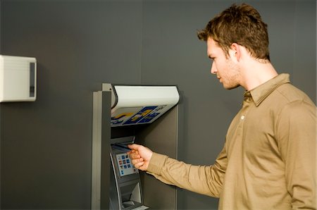 Young man using an ATM Stock Photo - Premium Royalty-Free, Code: 6108-05873610