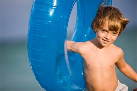 Boy holding an inflatable ring on the beach Stock Photo - Premium Royalty-Free, Code: 6108-05873849