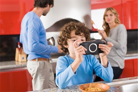 simsearch:6108-05863411,k - Boy playing a video game and his parents standing in the background Stock Photo - Premium Royalty-Free, Code: 6108-05873986