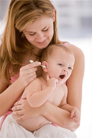 Woman cleaning her daughter's ear with a cotton swab Stock Photo - Premium Royalty-Free, Code: 6108-05874029