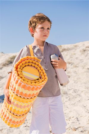 Boy carrying mat on the beach Stock Photo - Premium Royalty-Free, Code: 6108-05874374
