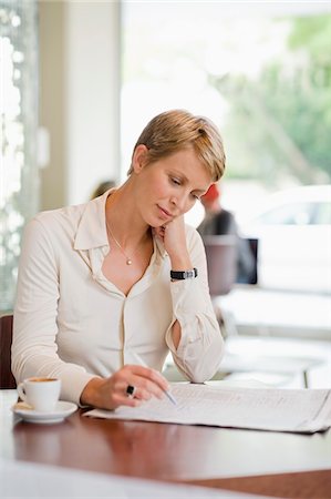 Businesswoman sitting in a restaurant and reading a financial newspaper Stock Photo - Premium Royalty-Free, Code: 6108-05874441