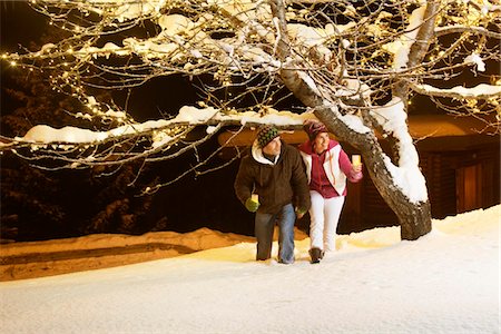 Young couple holding candles, walking in snow by night Stock Photo - Premium Royalty-Free, Code: 6108-05874584
