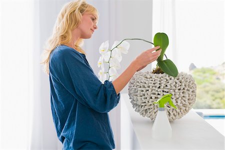 Woman looking at a houseplant Stock Photo - Premium Royalty-Free, Code: 6108-05874513