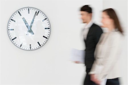 Business executives walking together in front of a wall clock Stock Photo - Premium Royalty-Free, Code: 6108-05874666