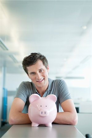 Businessman smiling near a piggy bank Stock Photo - Premium Royalty-Free, Code: 6108-05874791