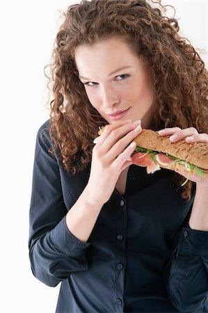female smirk - Woman eating a sandwich Stock Photo - Premium Royalty-Free, Code: 6108-05874804