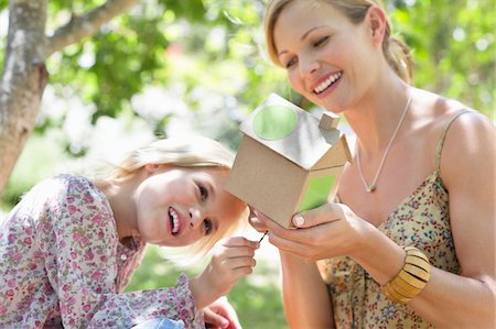 Little girl and her mother looking at dollhouse outdoors Stock Photo - Premium Royalty-Free, Code: 6108-05875051