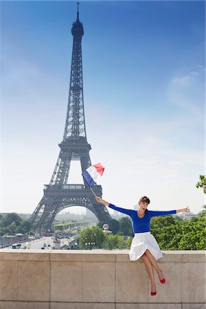 paris one woman - Femme tenant un drapeau français assis sur un mur de pierre avec la tour Eiffel en arrière-plan, Paris, Ile-de-France, France Photographie de stock - Premium Libres de Droits, Code: 6108-05875194
