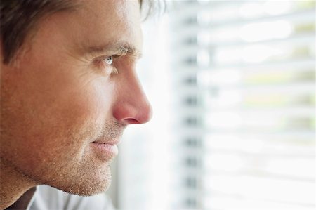 Close-up of a man looking through a window and thinking Stock Photo - Premium Royalty-Free, Code: 6108-06166017