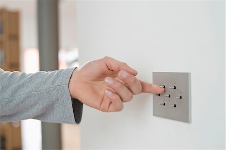 Close-up of a man's hand pressing light switch on a wall Stock Photo - Premium Royalty-Free, Code: 6108-06166274