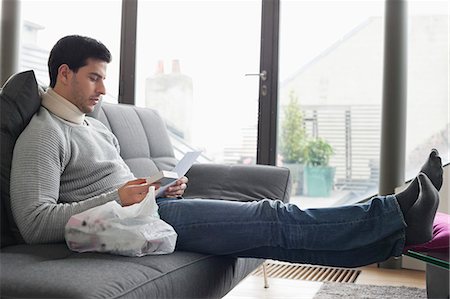 Man sitting on a couch reading medical prescription Stock Photo - Premium Royalty-Free, Code: 6108-06166276