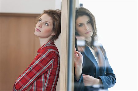 Two female friends standing back to back against a door Stock Photo - Premium Royalty-Free, Code: 6108-06166375