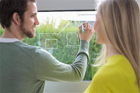 Woman looking at an architect drawing a design on the window glass Stock Photo - Premium Royalty-Free, Code: 6108-06166525