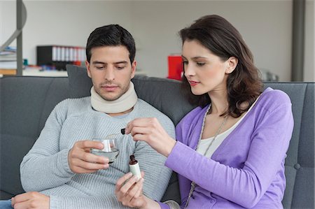 Woman giving medicine to her husband suffering from neckache Stock Photo - Premium Royalty-Free, Code: 6108-06166612
