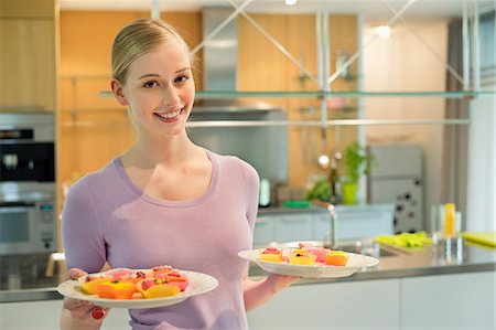 simsearch:6108-05869331,k - Happy woman holding two plates of cup cakes Stock Photo - Premium Royalty-Free, Code: 6108-06166735