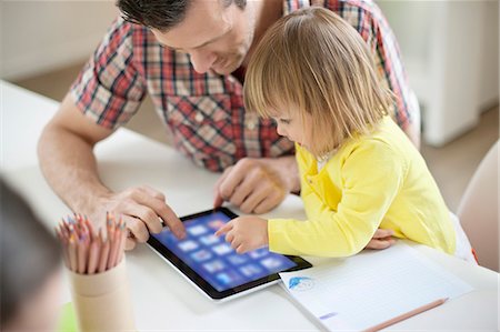 Man teaching digital tablet to his daughter Stock Photo - Premium Royalty-Free, Code: 6108-06166937