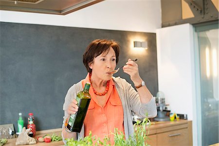 simsearch:6108-06167085,k - Elderly woman tasting olive oil in the kitchen Stock Photo - Premium Royalty-Free, Code: 6108-06167088