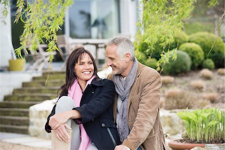 Romantic couple sitting in a garden and smiling Stock Photo - Premium Royalty-Free, Code: 6108-06167169