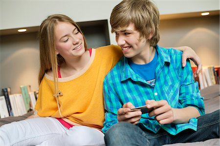 simsearch:6108-06907036,k - Teenage boy with his sister using a mobile phone and smiling Stock Photo - Premium Royalty-Free, Code: 6108-06167281