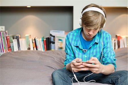 Teenage boy listening to music on iPod at home Stock Photo - Premium Royalty-Free, Code: 6108-06167284