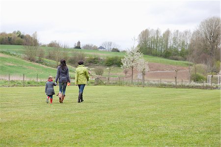 parents walking with kids - Girl walking with her mother and grandmother in a lawn Stock Photo - Premium Royalty-Free, Code: 6108-06167333