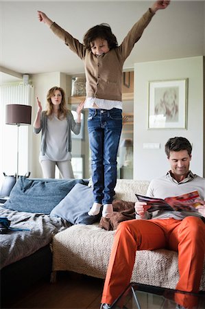 family home indoors - Naughty boy jumping on couch with his parents at home Stock Photo - Premium Royalty-Free, Code: 6108-06167531