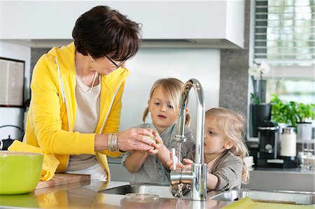 simsearch:6108-06167085,k - Elderly woman with her granddaughters washing in a kitchen Stock Photo - Premium Royalty-Free, Code: 6108-06167612