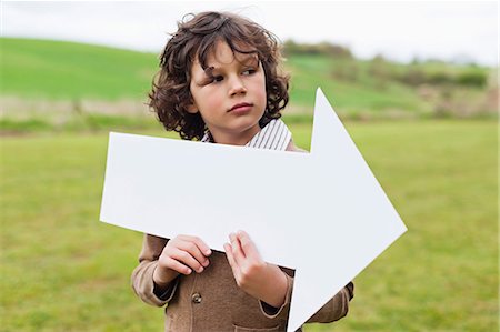 farm and boys - Boy holding an arrow sign in a field Stock Photo - Premium Royalty-Free, Code: 6108-06167865