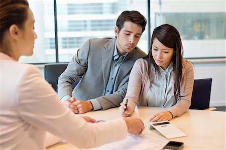 Couple signing documents with business executive Stock Photo - Premium Royalty-Free, Code: 6108-06167917