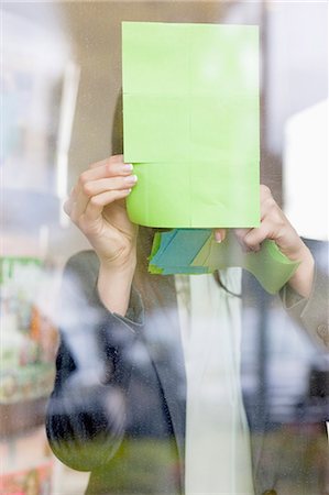 Businesswoman sticking memo notes on glass in an office Stock Photo - Premium Royalty-Free, Code: 6108-06168328