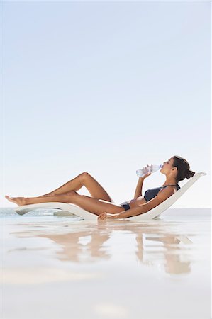 Beautiful woman drinking water on the beach Stock Photo - Premium Royalty-Free, Code: 6108-06904696