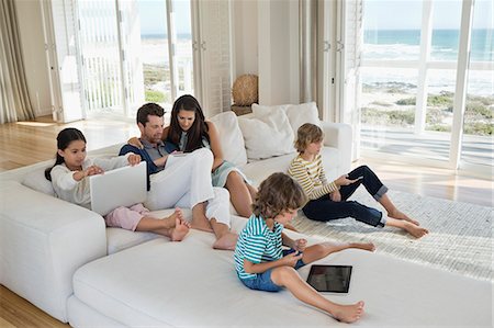family indoors house parent ethnic not beach not park - Family using electronics gadget Stock Photo - Premium Royalty-Free, Code: 6108-06904850