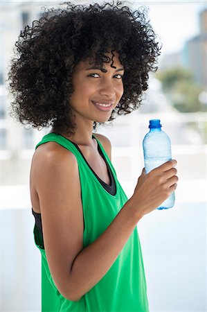 Portrait of a woman holding a water bottle and smiling Stock Photo - Premium Royalty-Free, Code: 6108-06904805