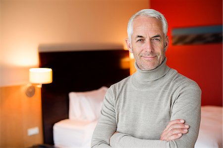 portrait 50s alone - Portrait of a man smiling with arms crossed in a hotel room Stock Photo - Premium Royalty-Free, Code: 6108-06904947