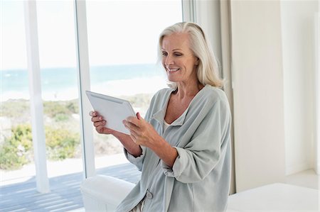 simsearch:6108-06904945,k - Woman using a digital tablet and smiling at home Stock Photo - Premium Royalty-Free, Code: 6108-06905076