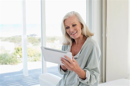 simsearch:6108-06904945,k - Woman using a digital tablet and smiling at home Stock Photo - Premium Royalty-Free, Code: 6108-06905097