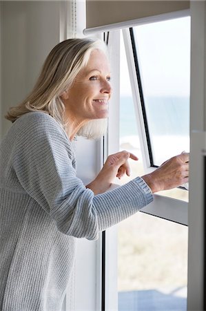 Woman looking through a window Stock Photo - Premium Royalty-Free, Code: 6108-06905094