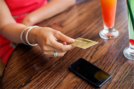 person on phone with credit card - Woman paying with a credit card on a table in a restaurant Stock Photo - Premium Royalty-Free, Code: 6108-06905002