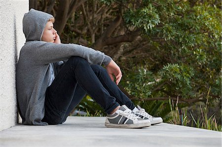 Teenage boy leaning against a wall and thinking Stock Photo - Premium Royalty-Free, Code: 6108-06905206