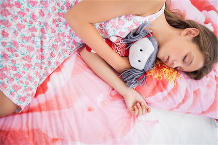 Girl sleeping on the bed with a rag doll Stock Photo - Premium Royalty-Free, Code: 6108-06905210